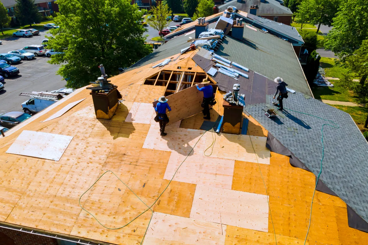 Roofers installing wood sheathing on a residential roof