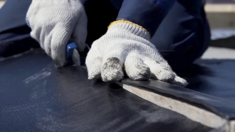 Worker cutting rubber roofing membrane